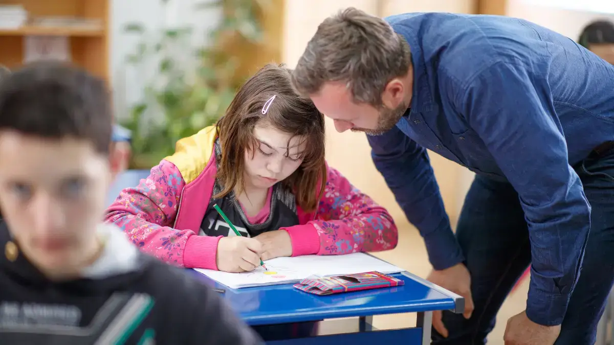 Insegnante di sostegno aiuta studente con disabilità durante attività di disegno in classe